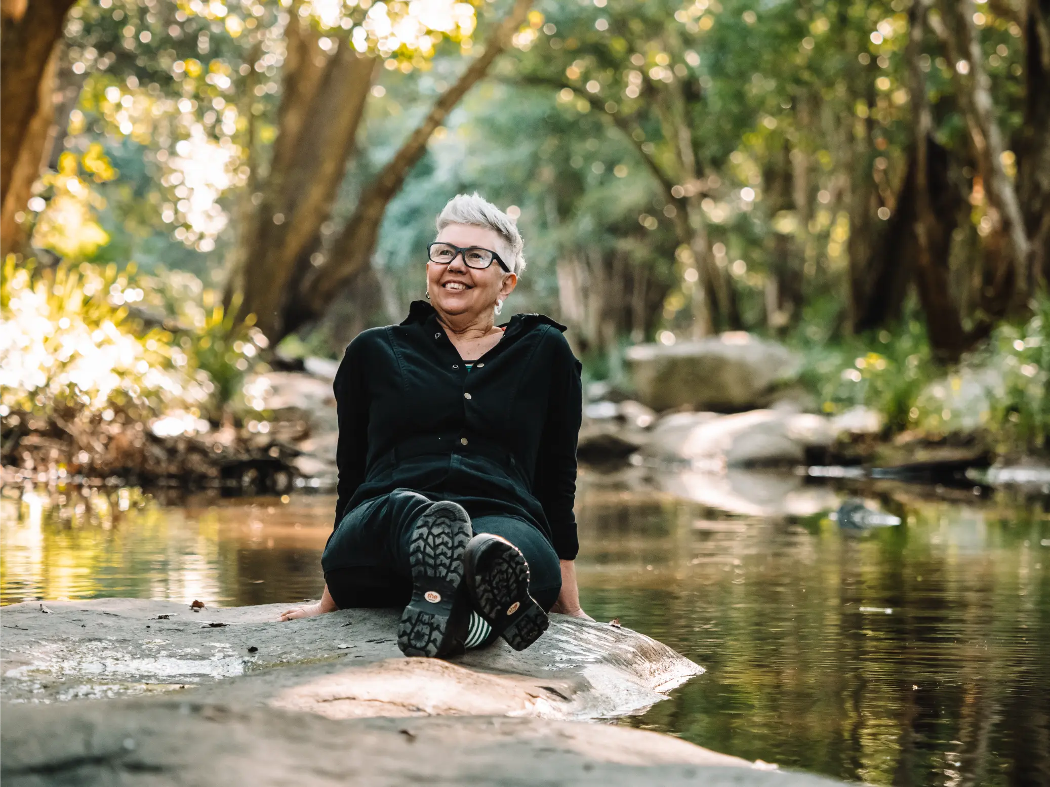 Person resting near a tranquil body of water, immersed in nature.